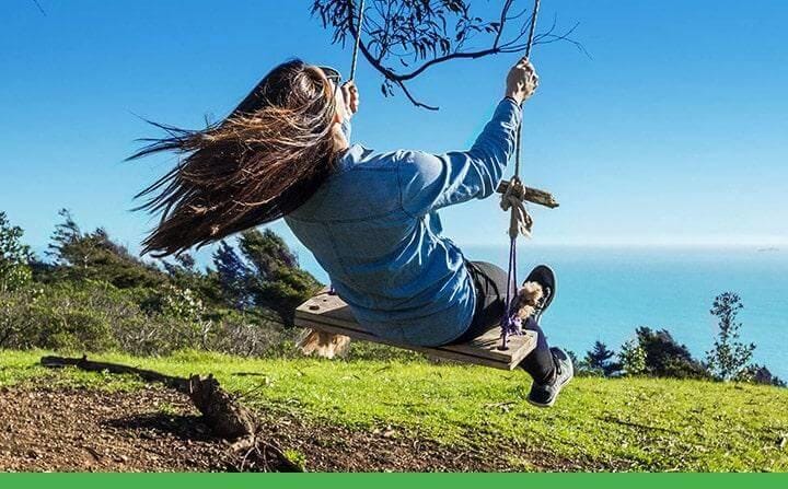 A woman swinging on a swing hanging from a tree